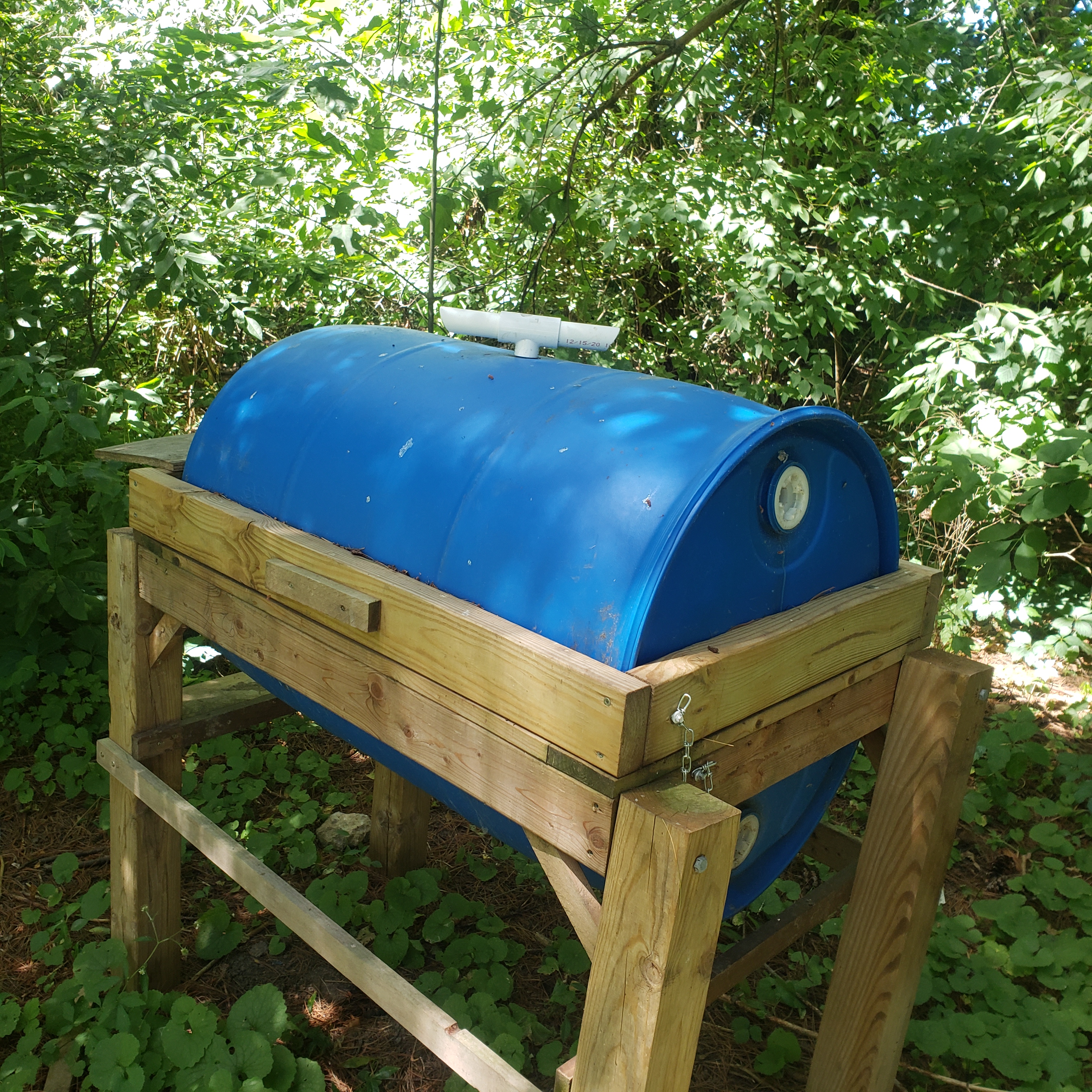 Figure 17. Front view of 55-gallon BSF larval rearing bin, closed. Featuring wooden handle, loose support chain, and Tee PVC joint for adult re-entrance.  (<em>Photo credit: Laura Ingwell</em>)