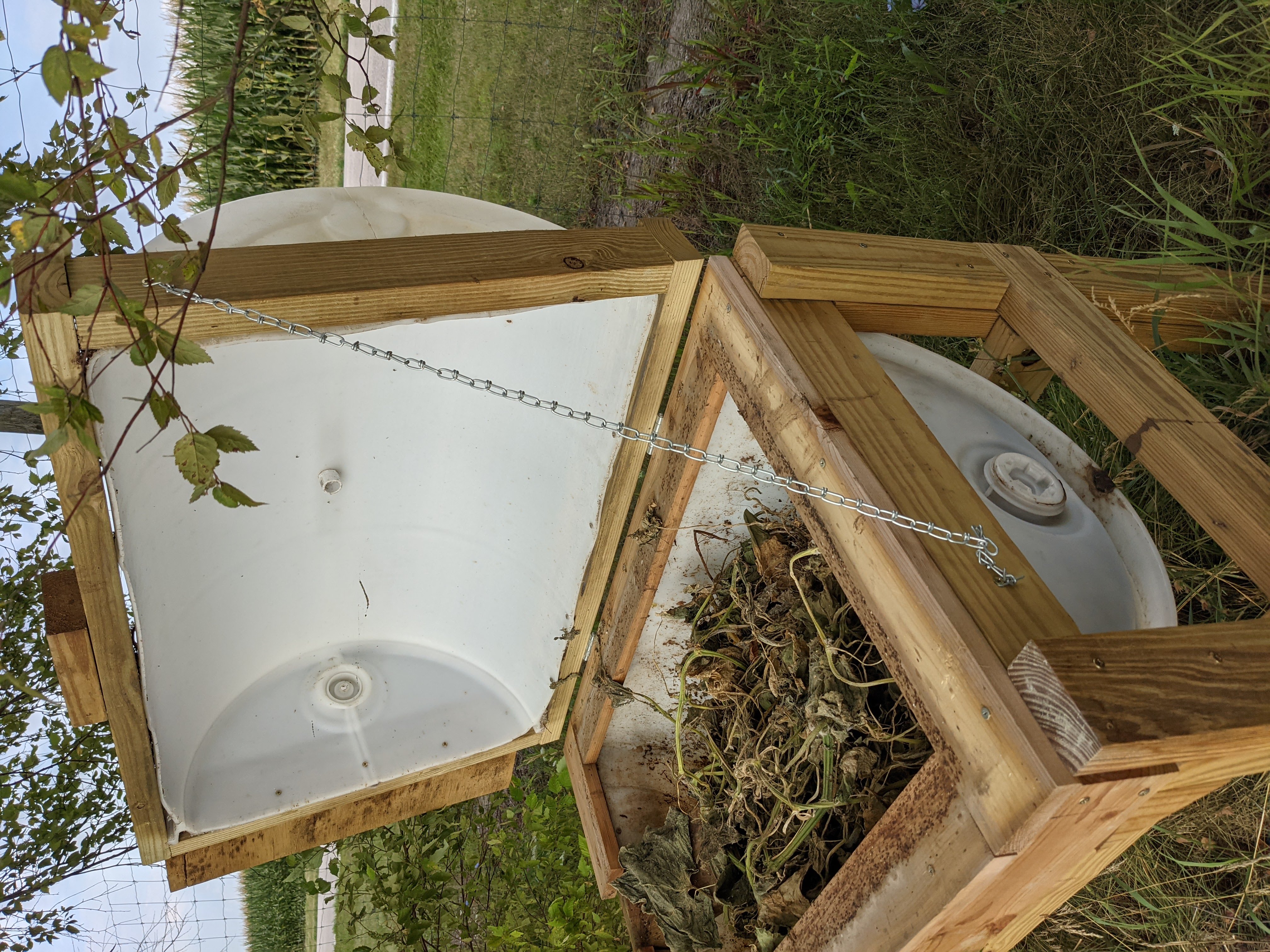 Figure 24. Side profile view of 55 gallon BSF larval rearing bin featuring fully extended support chain for the lid. Also features main drain hole. (<em>Photo credit: Catherine Terrell</em>)