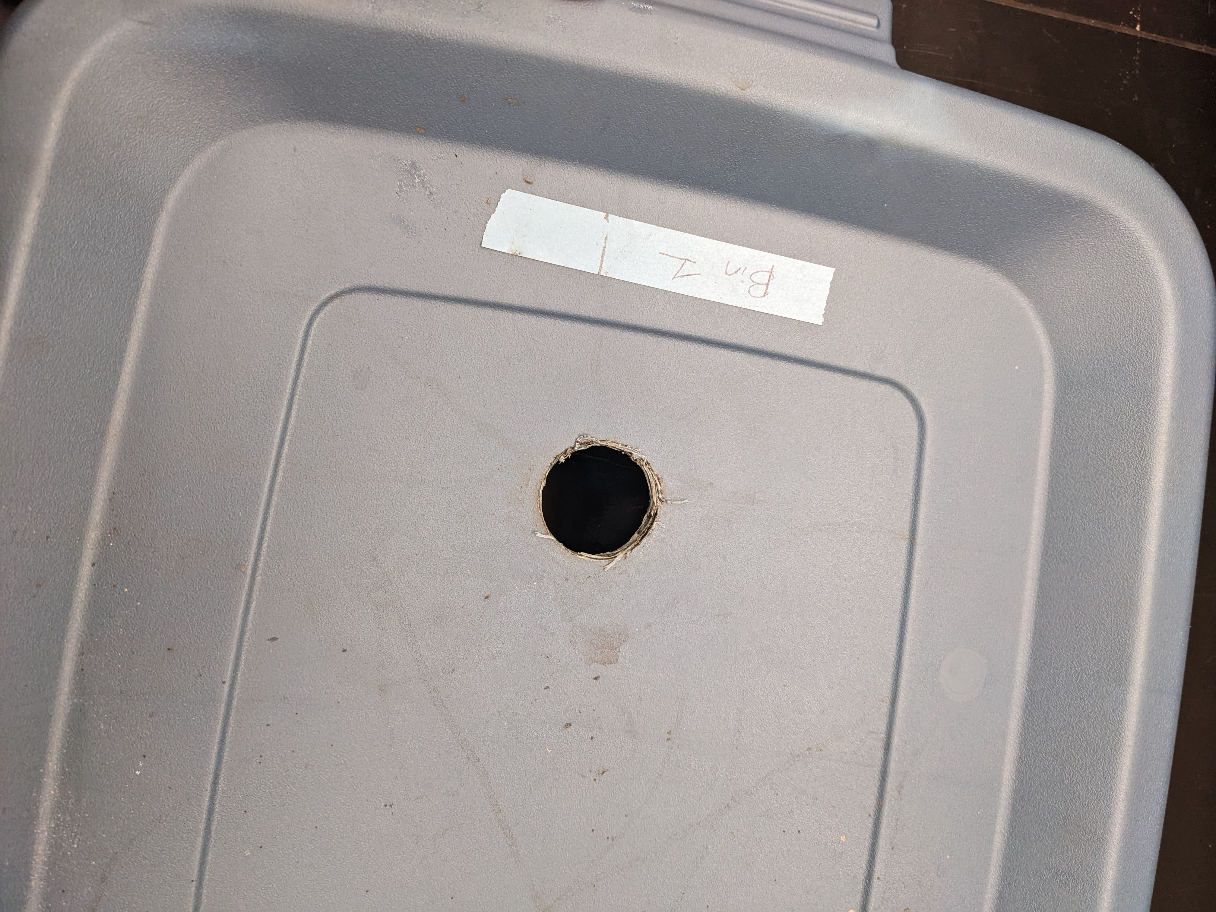 Figure 7. Top view of 18-gallon BSF larval rearing bin showing 1-inch circular opening for Tee PVC joint insertion. (<em>Photo credit: Catherine Terrell, Purdue Entomology</em>)